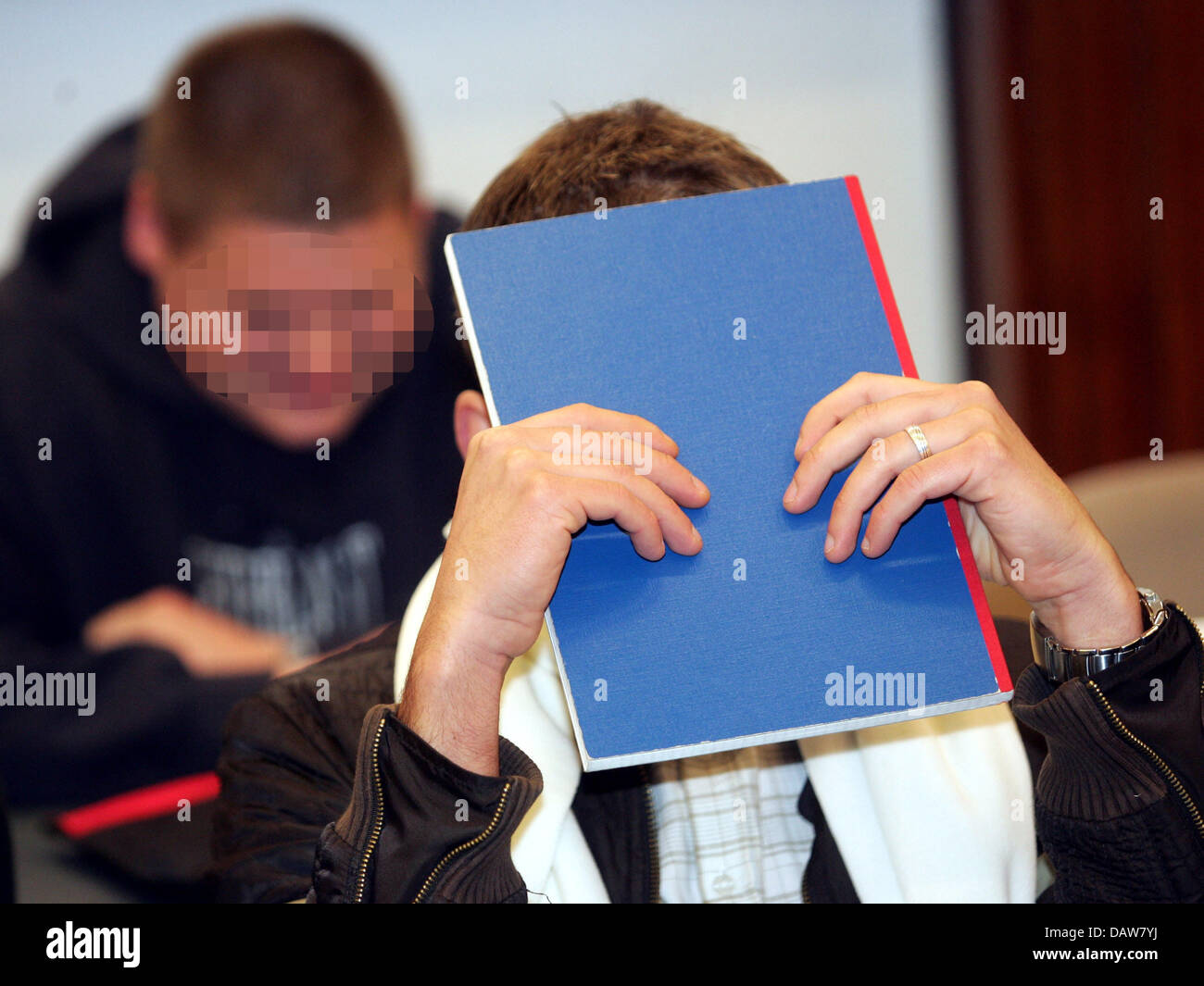 Defendant Lars K. (R) covers his face with a paper folder in the dock of District Court Magdeburg, Germany, Thursday, 08 March 2007. The prosecutor's office for the state of Saxony-Anhalt has filed charges against seven men accused of instigating the burning of books which included the famous Diary of Anne Frank. It is likely that the prosecutors announce today the judgement. Durin Stock Photo