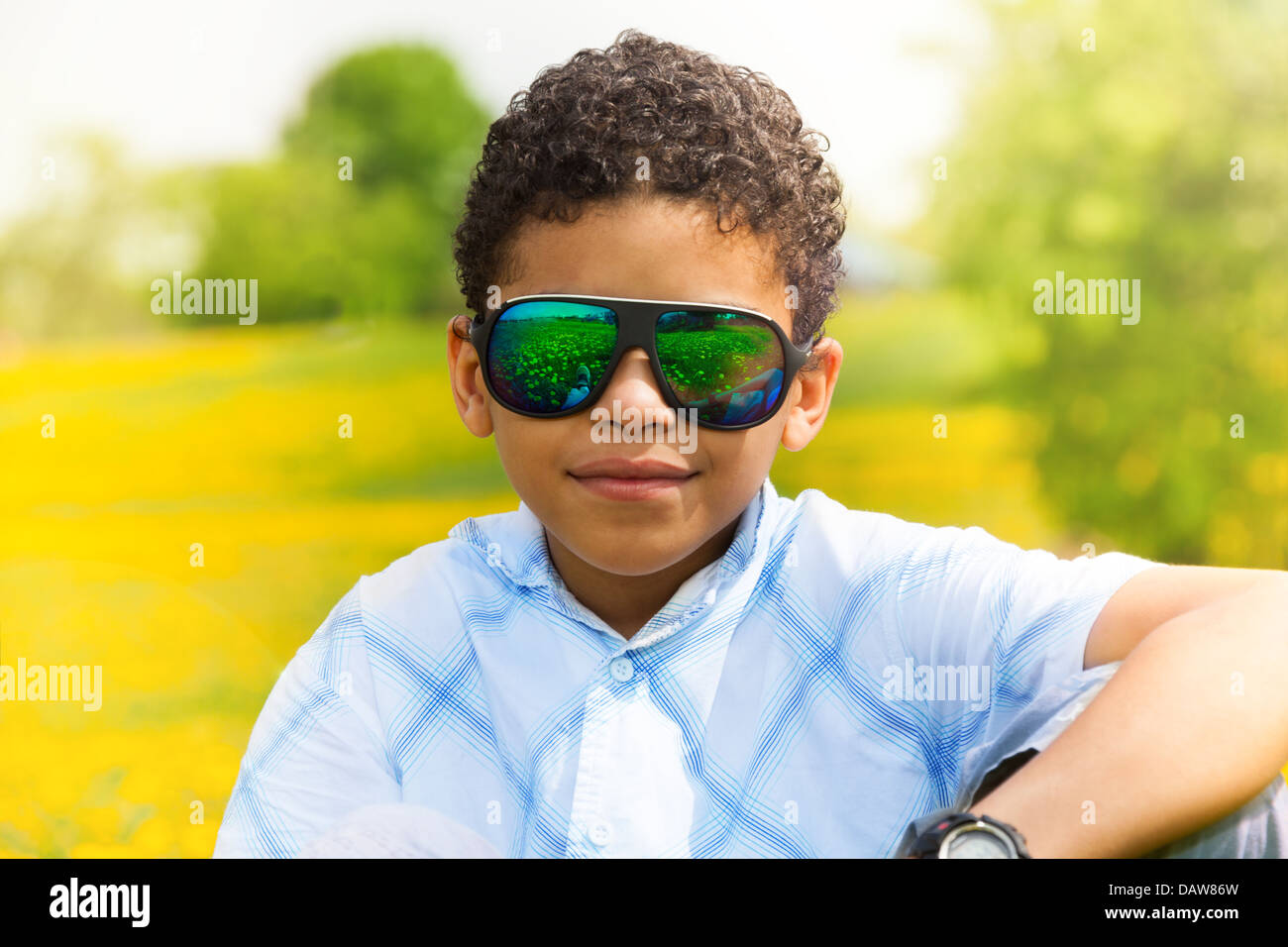 Close portrait of happy 10 years old black boy in sunglasses in the park Stock Photo