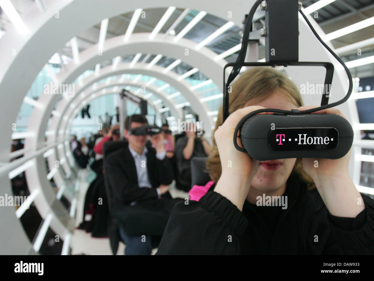 Visitors wear 3-D-glasses at the German Telekom AG booth during the 'CeBIT 2007' trade fair in Hanover, Germany, Thursday, 15 March 2007. CeBIT is the world's largest trade fair showcasing digital IT and telecommunications solutions for home and work environments and this year runs from 15th until 21st March 2007. More than 6,000 companies from 77 countries will exhibit their lates Stock Photo