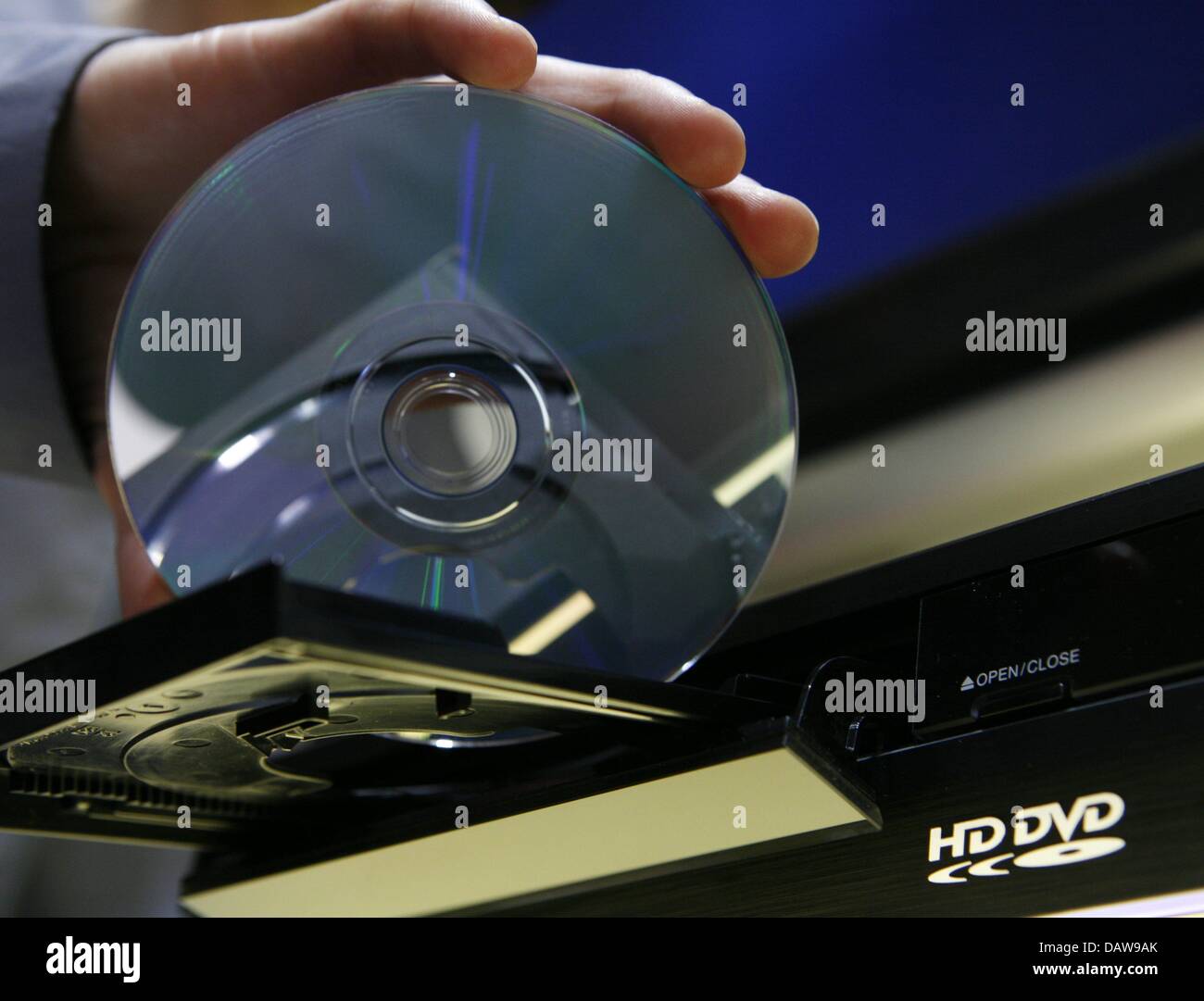 A person inserts a HD-DVD into a player at the 'CeBIT 2007' trade fair in Hanover, Germany, Thursday, 15 March 2007. The two formats HD-DVD and Blue-ray continue to compete for the succession of the CD and DVD systems at the world's largest trade fair showcasing digital IT and telecommunications solutions for home and work environments. The CeBIT runs from 15th until 21st March 200 Stock Photo
