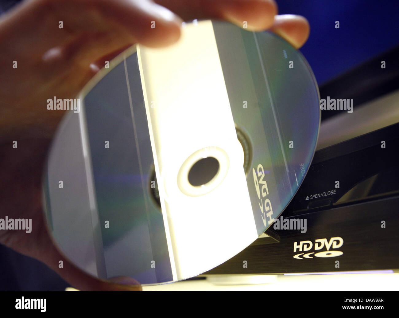 A person inserts a HD-DVD into a player at the 'CeBIT 2007' trade fair in Hanover, Germany, Thursday, 15 March 2007. The two formats HD-DVD and Blue-ray continue to compete for the succession of the CD and DVD systems at the world's largest trade fair showcasing digital IT and telecommunications solutions for home and work environments. The CeBIT runs from 15th until 21st March 200 Stock Photo