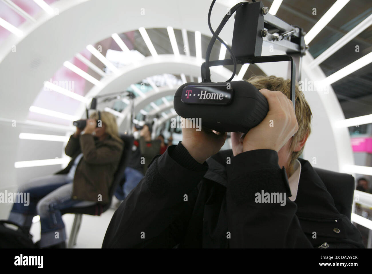Visitors look through 3-D-glasses at the German Telekom AG booth during the 'CeBIT 2007' trade fair in Hanover, Germany, Saturday 17 March 2007. CeBIT is the world's largest trade fair showcasing digital IT and telecommunications solutions for home and work environments and this year runs from 15th until 21st March 2007. More than 6,000 companies from 77 countries will exhibit thei Stock Photo