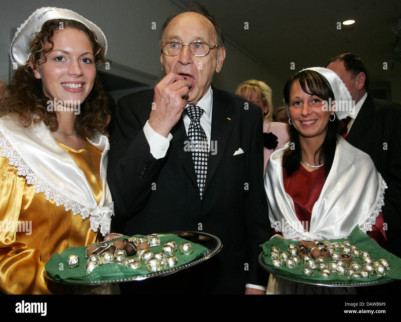 The former German Foreign Minister Hans-Dietrich Genscher (C) eats 'Halloren-Kugeln' sweets presented to him by Juliane (L) and Julia after the ceremony in honour of his 80th birthday at the 'Franckesche Stiftung' in Halle/Saale, Germany, Friday, 23 March 2007. Genscher was born 1927 in Halle. His birthplace shall be converted to a Stock Photo