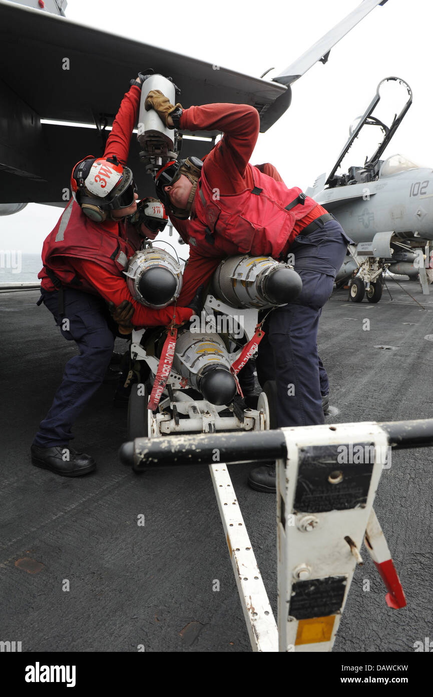 A US Navy Aviation ordnancemen offload a missile from a F/A-18C Hornet fighter aircraft following a mission on the flight deck of the aircraft carrier USS Nimitz July 15, 2013 in the Gulf of Oman. Stock Photo