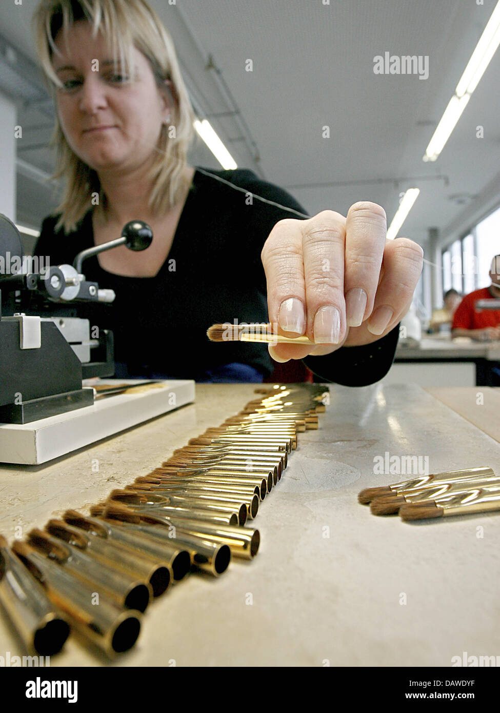 An employee puts brush parts together at the artist's brush factory