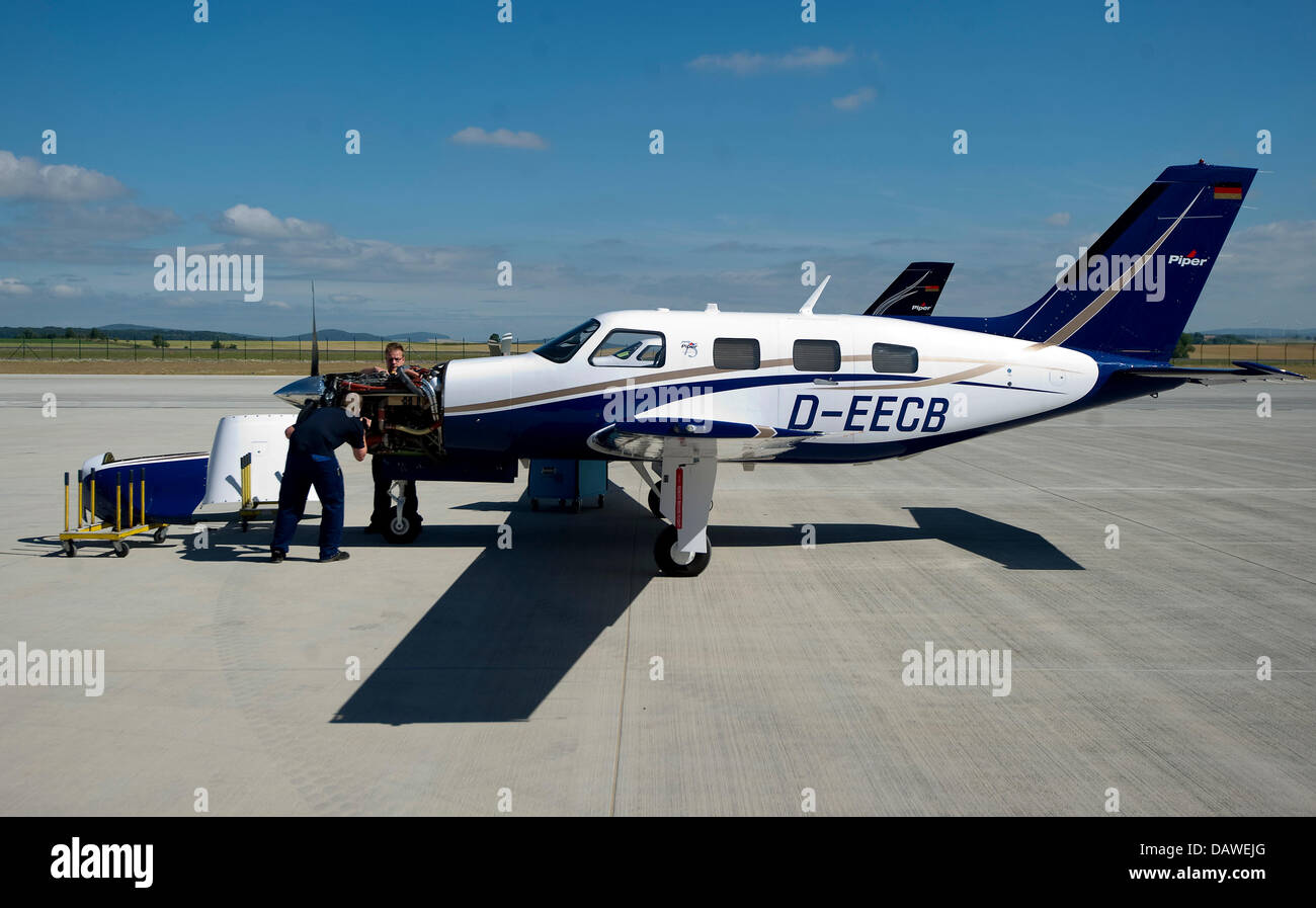 Two Piper employees check a plane outside of the new Piper building at the  airport in Kassel-Calden, Germany, 19 July 2013. The aircraft manufacturer  Piper has invested around 7 million euros in