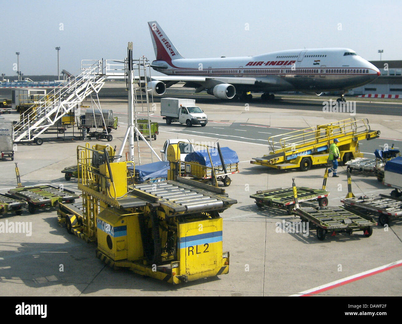 The photo shows an Air India Boeing 747 behind luggage carriers at the