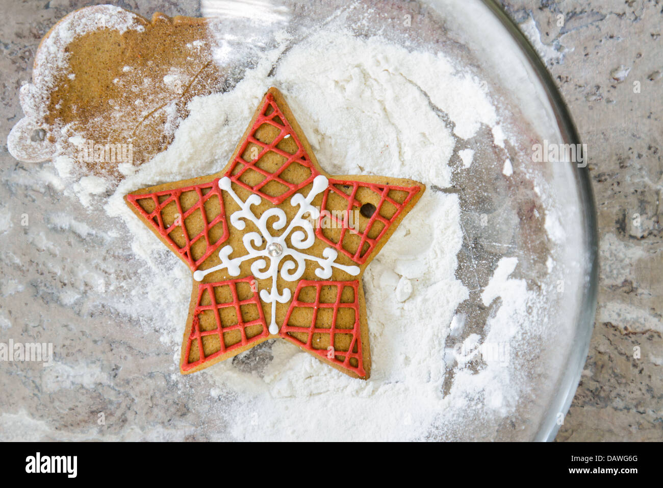 Starshaped festive gingerbread biscuit dropped into a bowl of flour