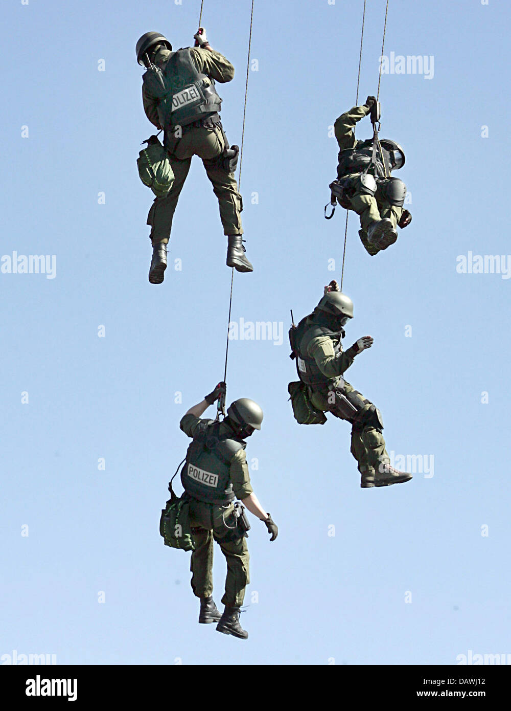 Four hooded and armed special unit policemen rope down from an ...