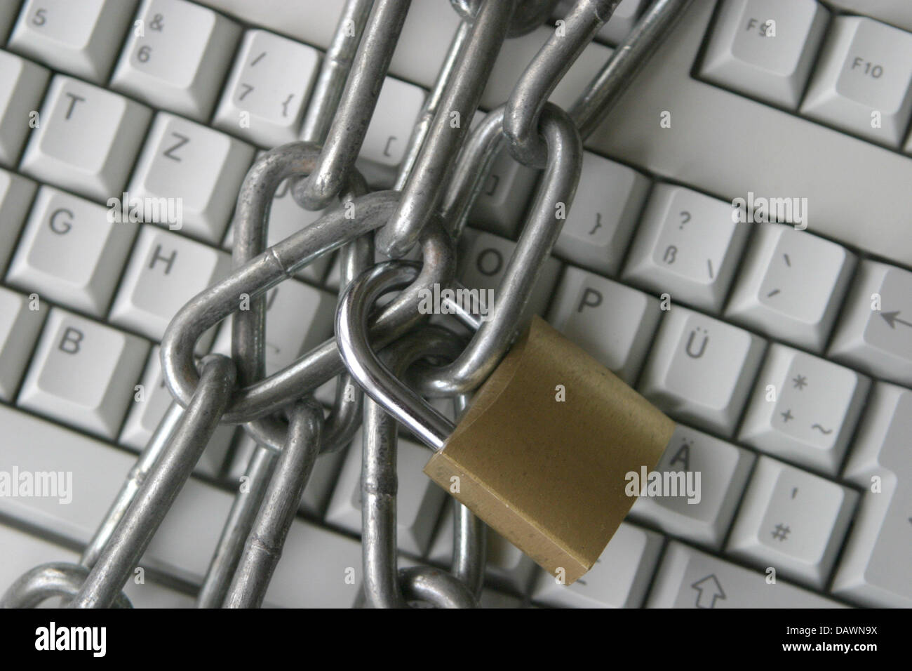 A steel chain connected by a padlock lies on top of a computer keyboard ...