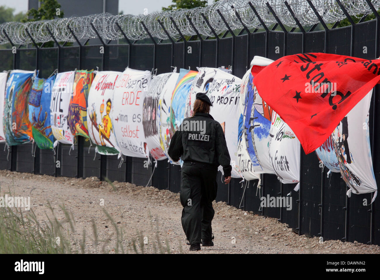An policewoman walks past banners at the security fence in Heiligendamm, Germany, 01 June 2007. The banners form part of the attac protest iniative 'Art Power Politics' accompanying the G8-summit in Heiligendamm from 06 until 08 June 2007. Visitors have to keep a 200m safety distance to the art objects. Photo: Jens Buettner Stock Photo