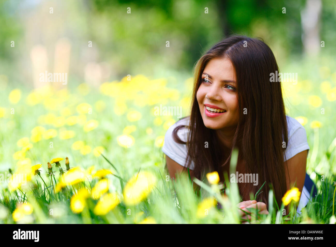 Beautiful young woman lying on grass with flowers Stock Photo - Alamy