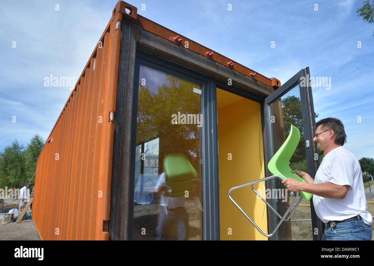 An employee of a furnishing company carries furniture into a container in students village Plaenterwald in Berlin, Germany, 19 July 2013. Students can move into the rebuilt freight containers from next semester starting in October. Photo: BRITTA PEDERSEN Stock Photo