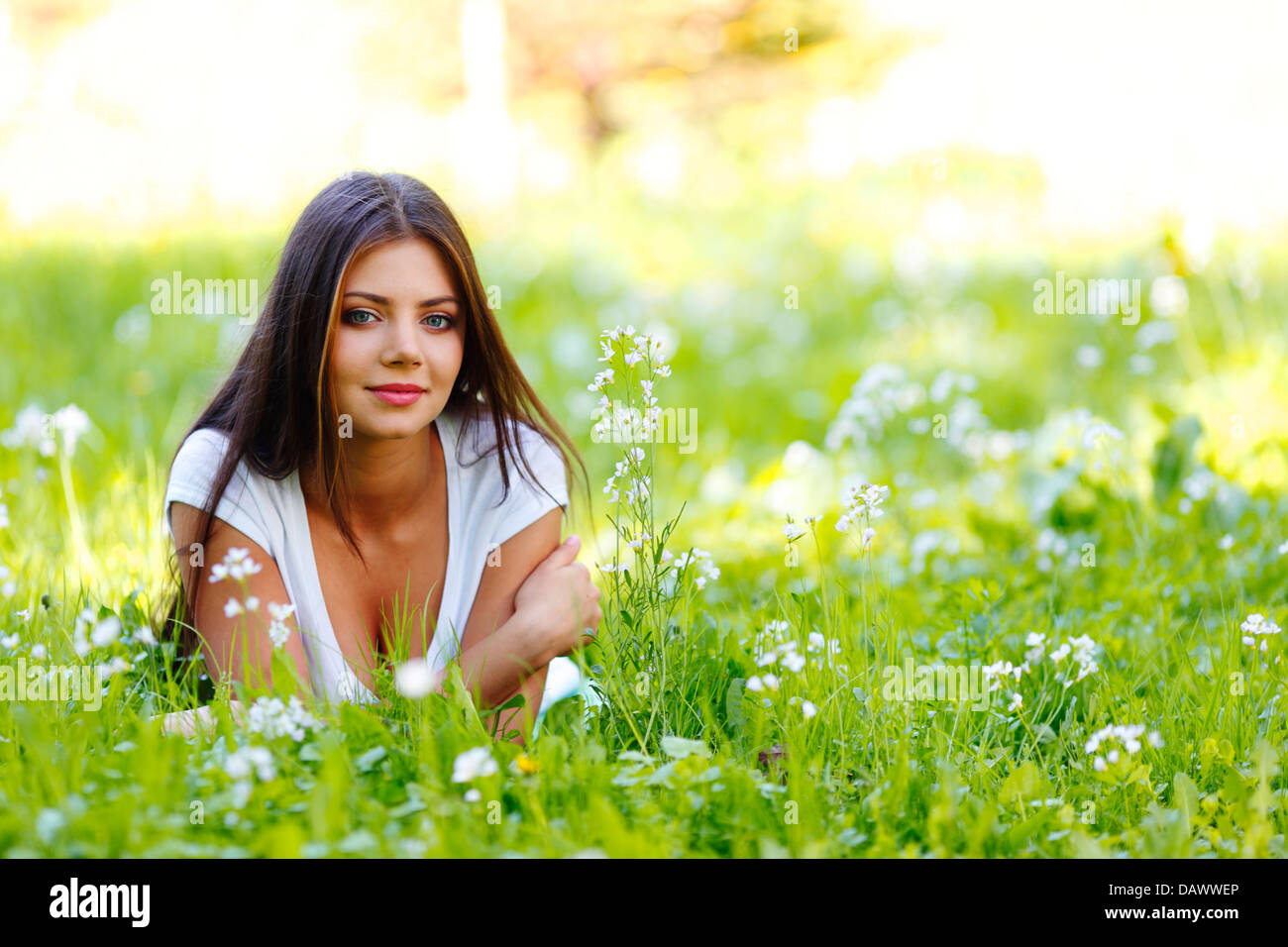 Beautiful young woman lying on grass with flowers Stock Photo - Alamy