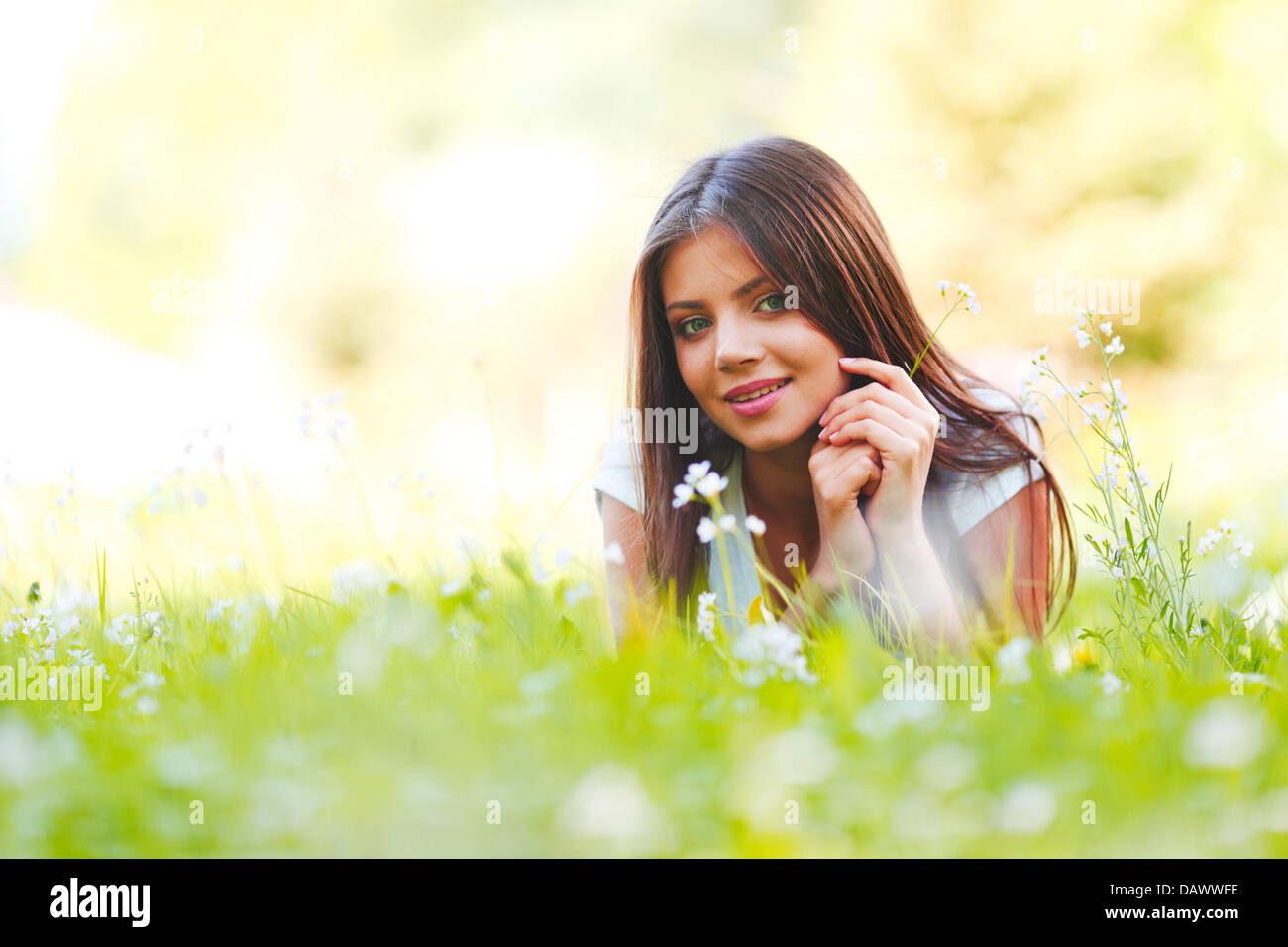Beautiful young woman lying on grass with flowers Stock Photo - Alamy