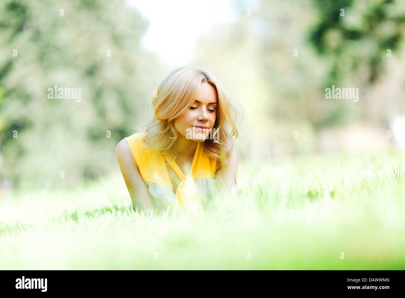 Happy young woman lying on grass Stock Photo - Alamy
