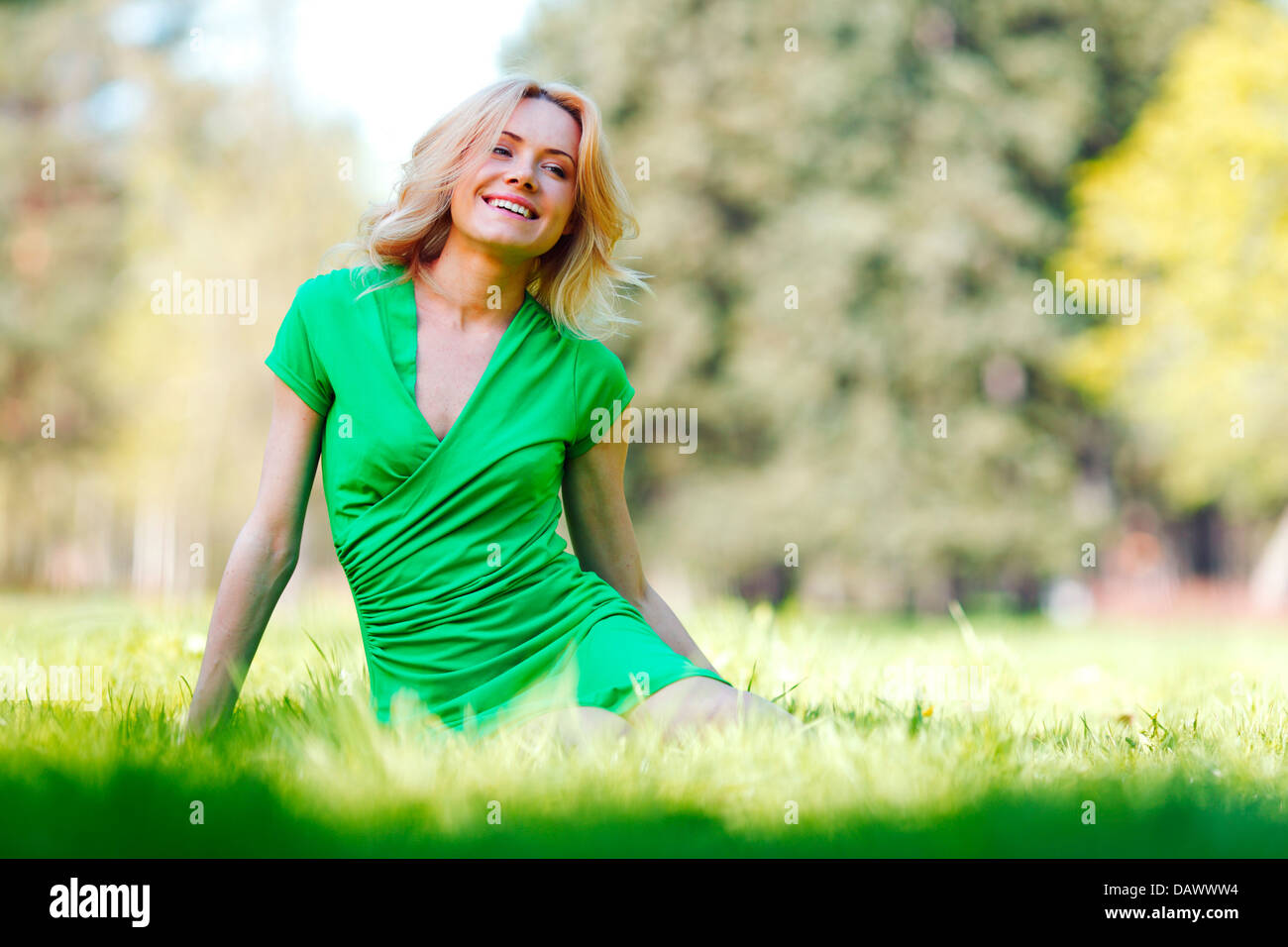 Happy young woman sitting on grass Stock Photo - Alamy