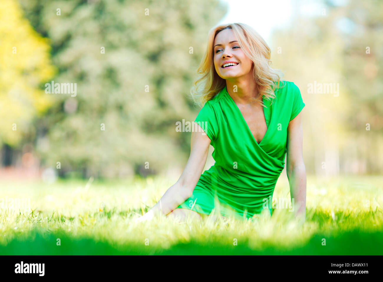Happy young woman sitting on grass Stock Photo - Alamy