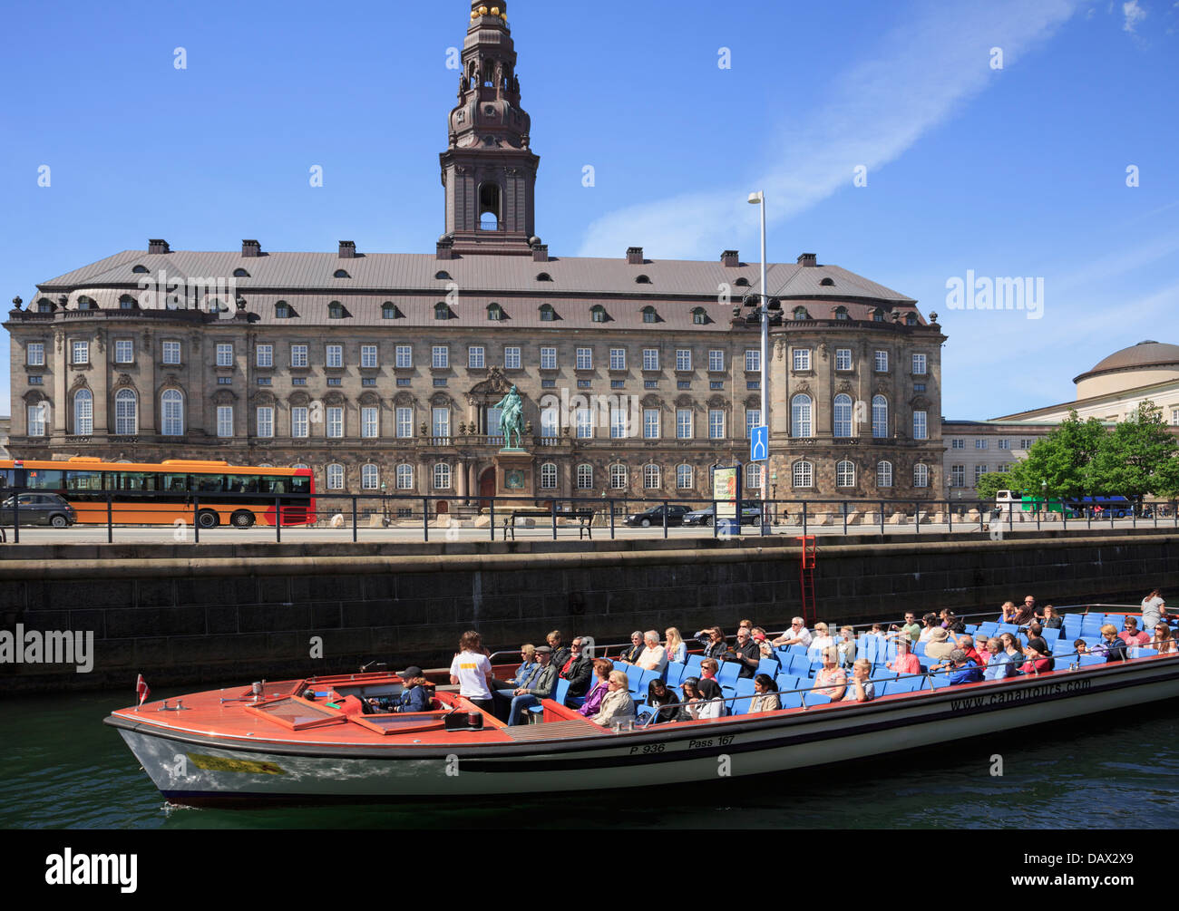 Tourists canal boat city sightseeing tour passing Christiansborg Palace on Slotsholmen Isle in Copenhagen, Zealand, Denmark Stock Photo