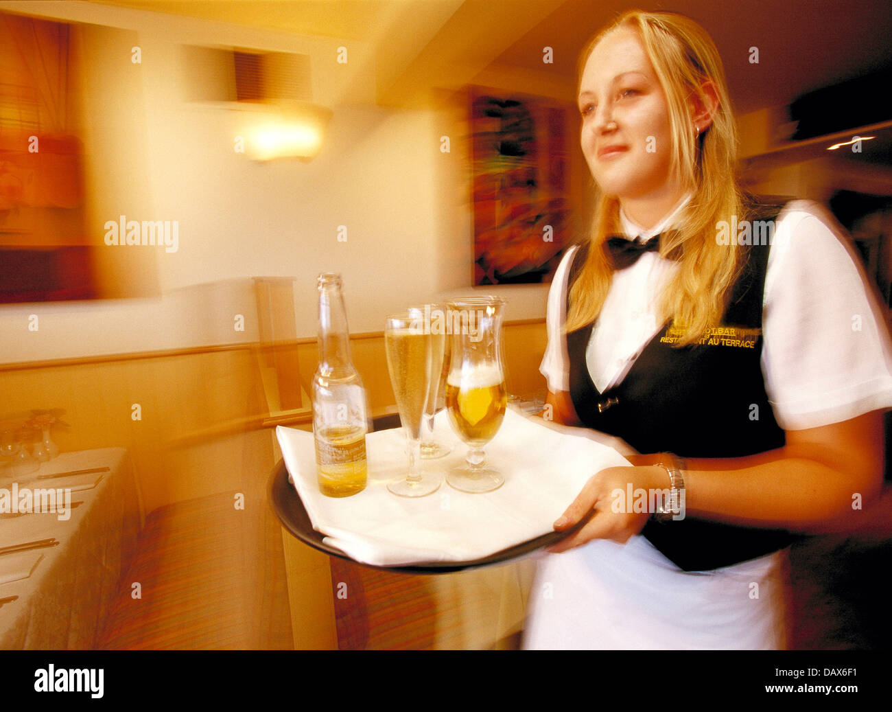 Attractive young blond woman waitress with drinks tray in café restaurant bar. Stock Photo