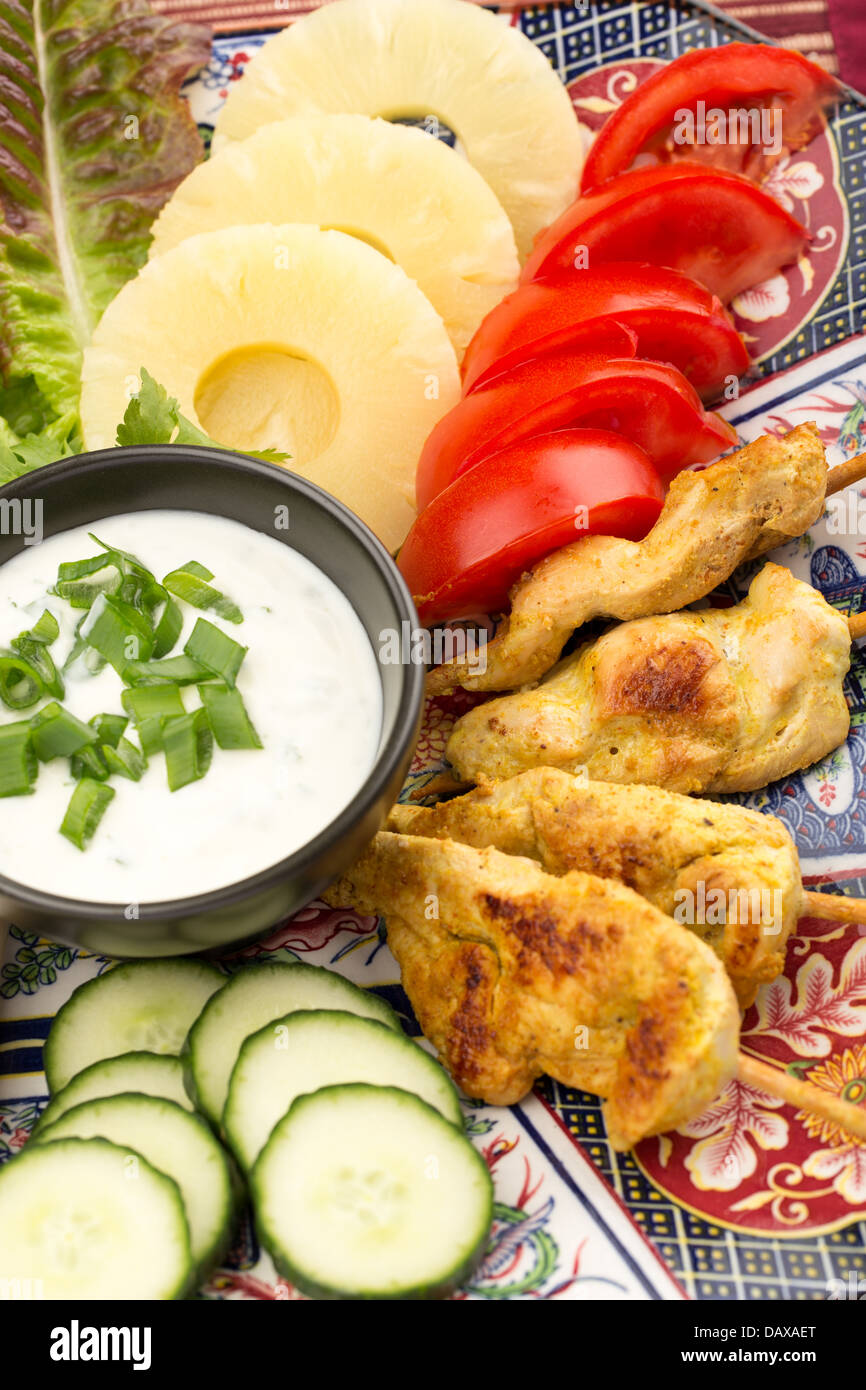 Asian food with chicken skewers, sauce, tomatoes, cucumber, pineapples and salad. Stock Photo
