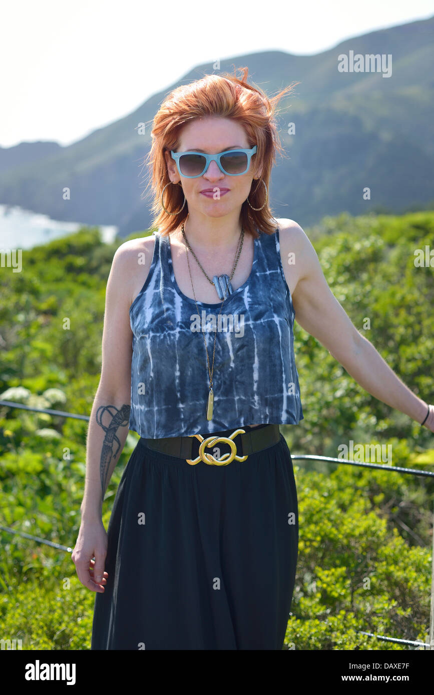 Attractive redhead posing outdoors in blue sunglasses Stock Photo