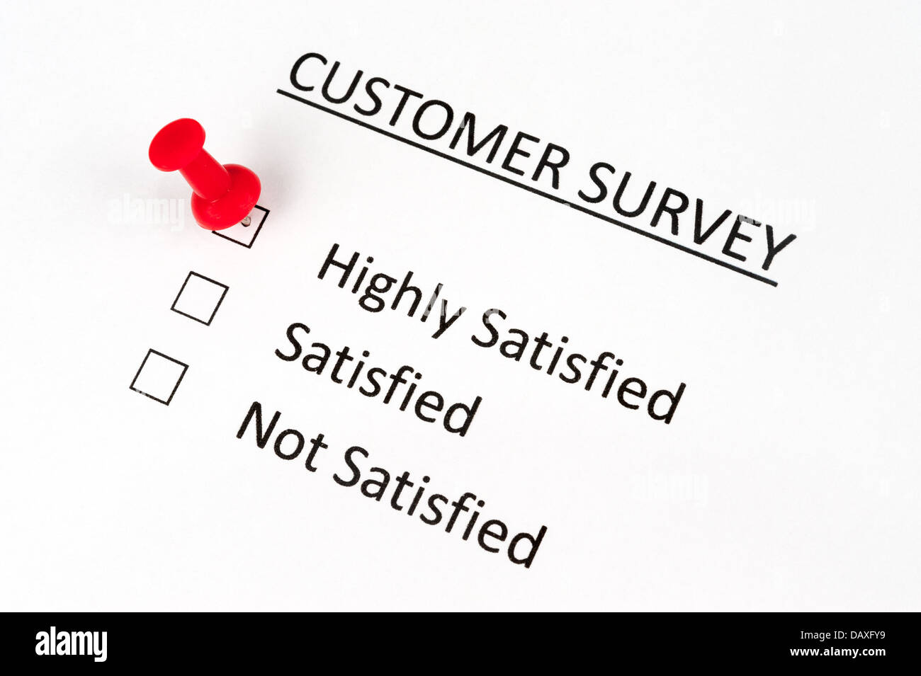 A thumbtack pinned on customer survey paper with options of highly satisfied, satisfied and not satisfied Stock Photo