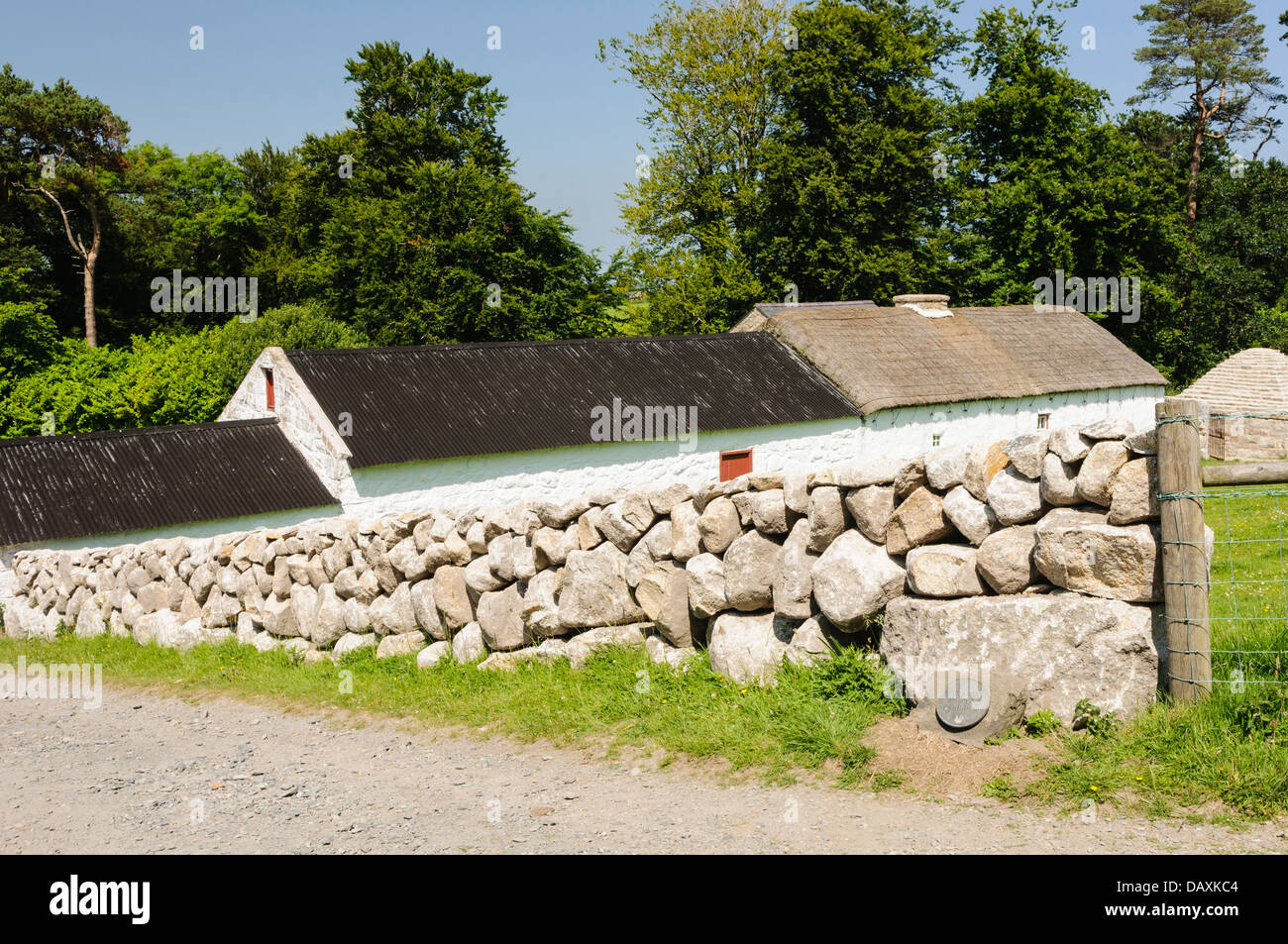 Dry stone walls leading down to a whitewashed Irish farmhouse Stock Photo