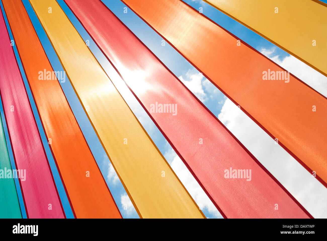 Multi-coloured ribbons lit by bright sunlight against a summer sky. Stock Photo