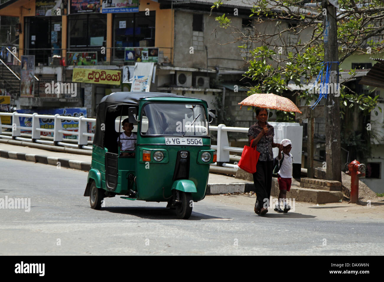 TUC TUC & PEDESTRIANS WITH UMBRELLA PERADENIYA SRI LANKA 12 March 2013 Stock Photo