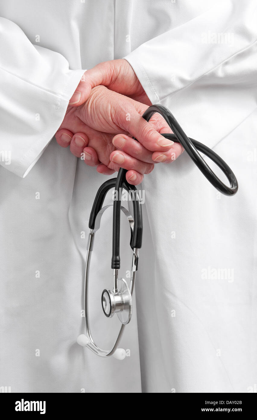 woman doctor in white coat holding stethoscope behind back Stock Photo