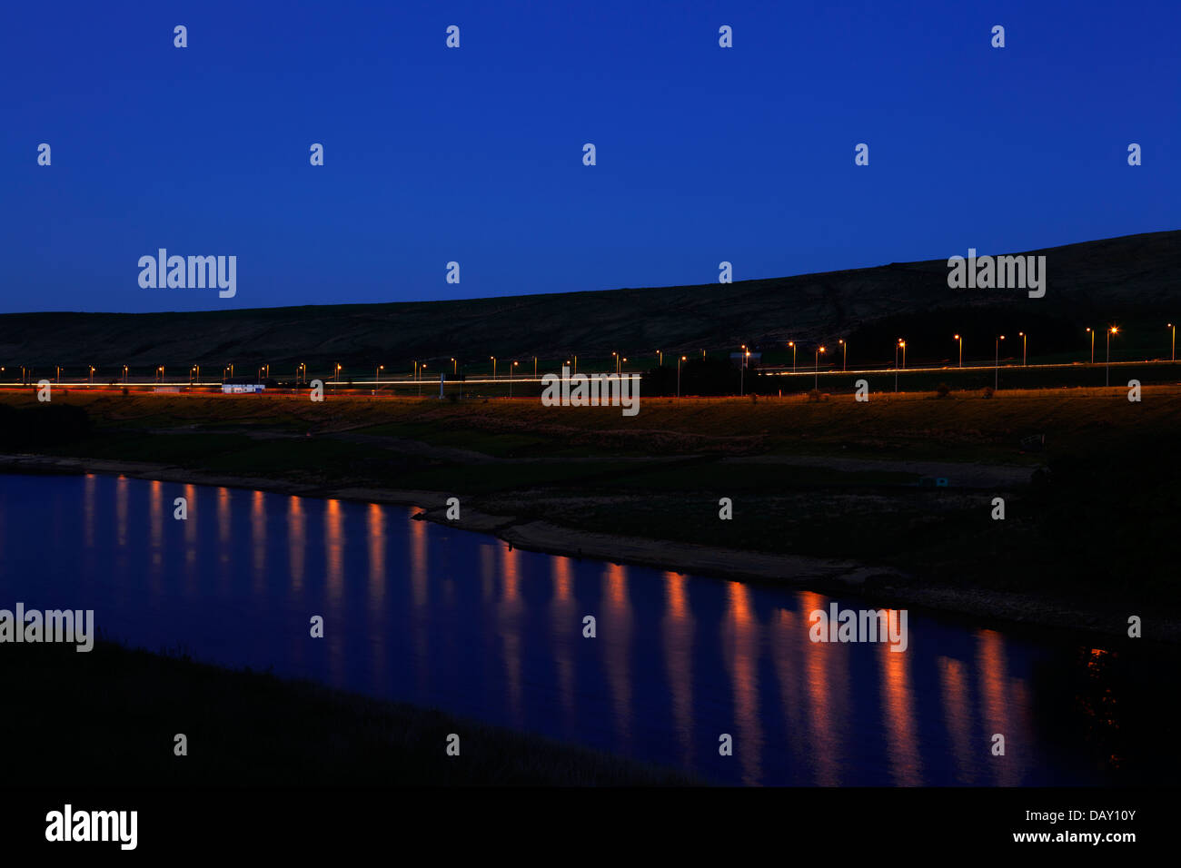 M62 motorway at dusk reflected in Booth Wood reservoir, Rishworth, West Yorkshire Stock Photo