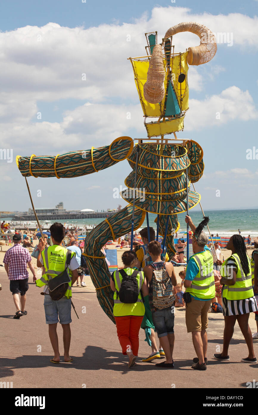 Bournemouth, UK. 20th July, 2013.  A day of sensory delights, a feast of colour, music and dance. An African Caribbean style carnival procession takes place going along the beach seafront delighting visitors, as part of the Bournemouth Masquerade Festival, produced by Umoja Arts Network with dazzling vibrant costumes, sculpture and puppets performing to the sounds of the Caribbean. The event involves Bournemouth schools, some brilliant artists, and the local African Caribbean community to celebrate the rich cultural diversity in Bournemouth. © Carolyn Jenkins/Alamy Stock Photo