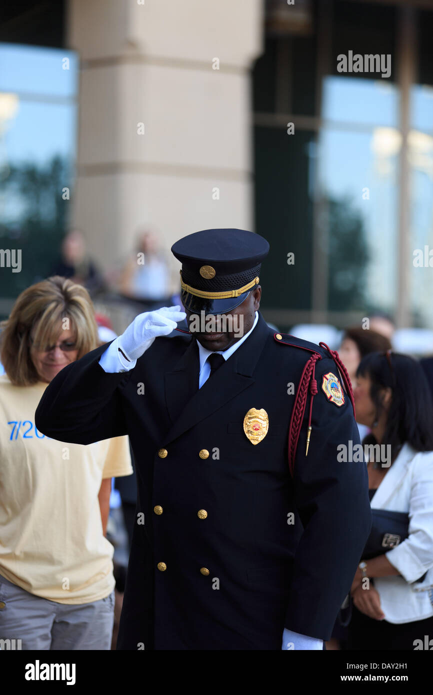 Aurora, Colorado, 20th July 2013. A fireman from the Aurora Fire Department salutes the memory of victims as a sign of respect at the remembrance wreath at the Aurora Municipal Center in Aurora Colorado on July 20, 2013. The wreath is meant as a way to remember and honor the victims of the Aurora Theater Batman shooting. Stock Photo