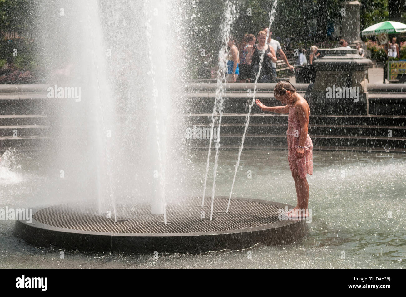 New York, NY 20 July  2013 - Summer heatwave, where temperatures have exceeded 90º farenheit, ( 33º Centigrade ) for the past week, a young girl cools off in the fountain in Washington Square Park.   On Thursday, electricity usage fell just short of an all-time high - 13,161 megawatts were used by 5 p.m., just 28 megawats fewer than a record set on July 22, 2011, Con Edison said, which lead to power outages on Staten Island. City officials urged New Yorkers to avoid exercising outdoors, drink plenty of water and check on any elderly neighbors. Stock Photo