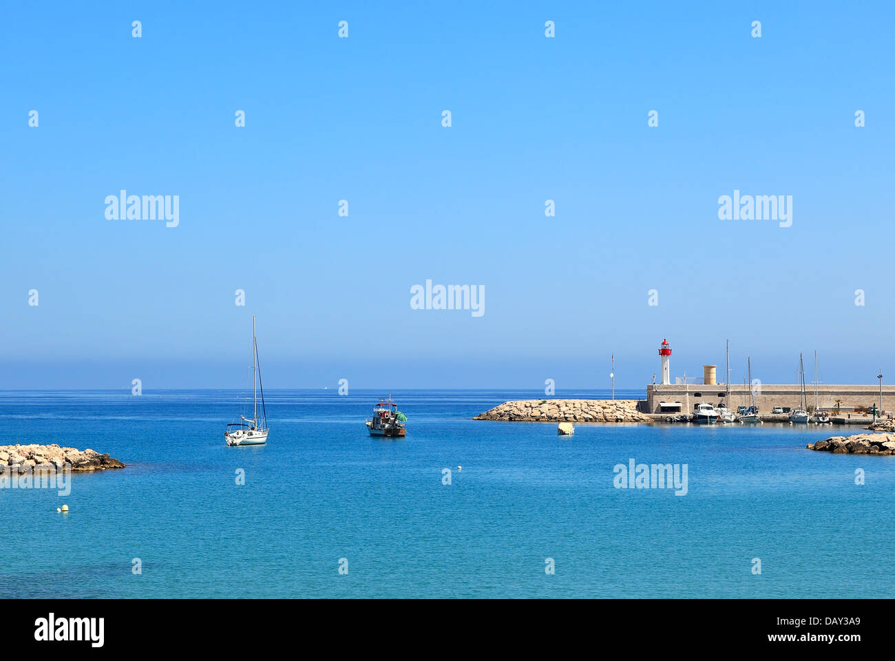 View of yachts and boats floating on calm surface of Mediterranean sea at the entrance to marina in Menton, France. Stock Photo