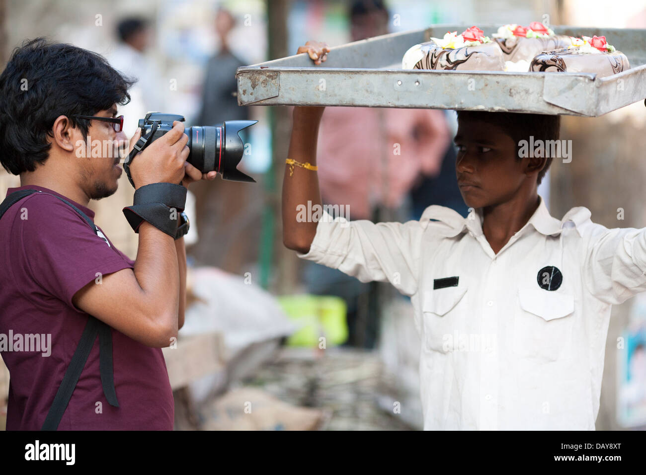 A student photographer takes a photograph with a Canon camera of a man on the streets of the old city of Dhaka in Bangladesh. Stock Photo