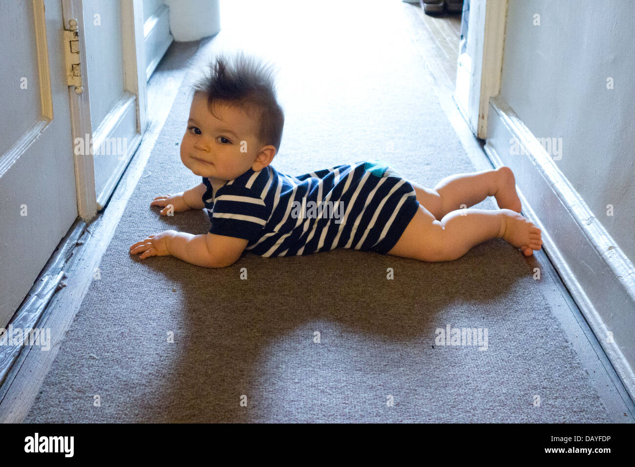 baby boy learning to crawl on rug Stock Photo