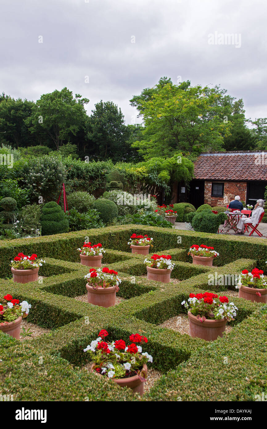 West Green House Garden - visitors relax in the Alice Garden: box hedges  form a checkerboard with pot plants in red & white Stock Photo - Alamy