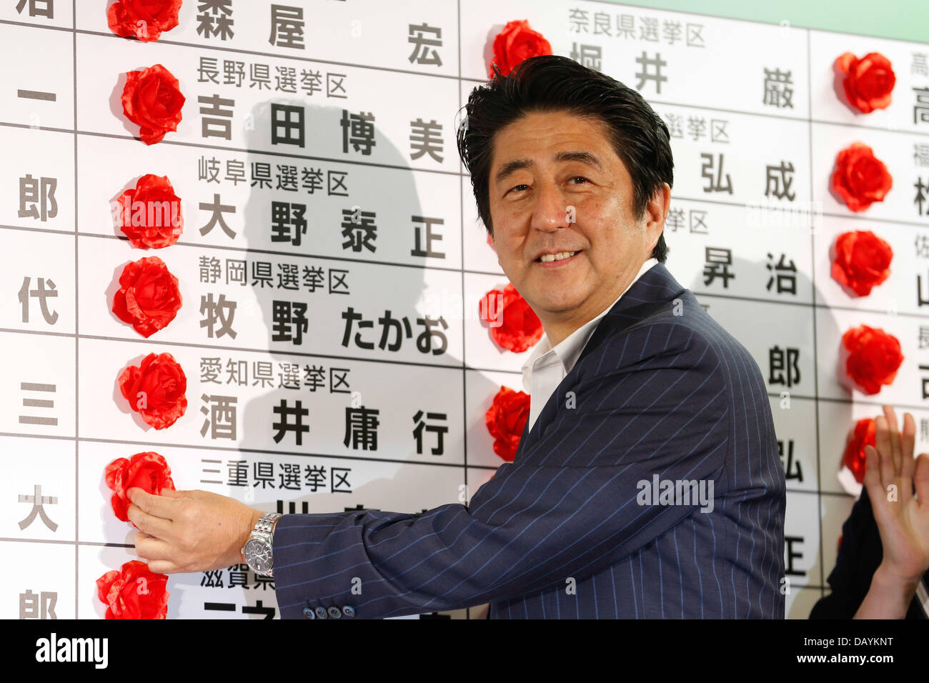 Tokyo, Japan. 21st July, 2013. Shinzo Abe, center, Japan's prime minister and president of the ruling Liberal Democratic Party, pins a paper rose on the name of a winning candidate at the party's election headquarters in Tokyo on Sunday, July 21, 2013. A decisive victory by Abe's coalition bloc in Sunday's upper house election would give him a a total control of both houses of parliament, setting the stage for Japan's first stable government since 2006. Credit:  AFLO/Alamy Live News Stock Photo