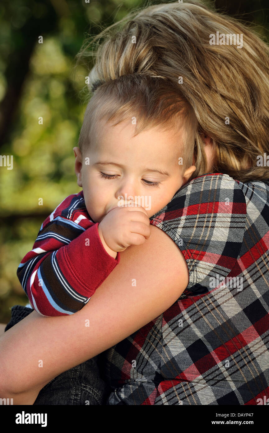 One year old boy sleeping on his mothers shoulder Stock Photo