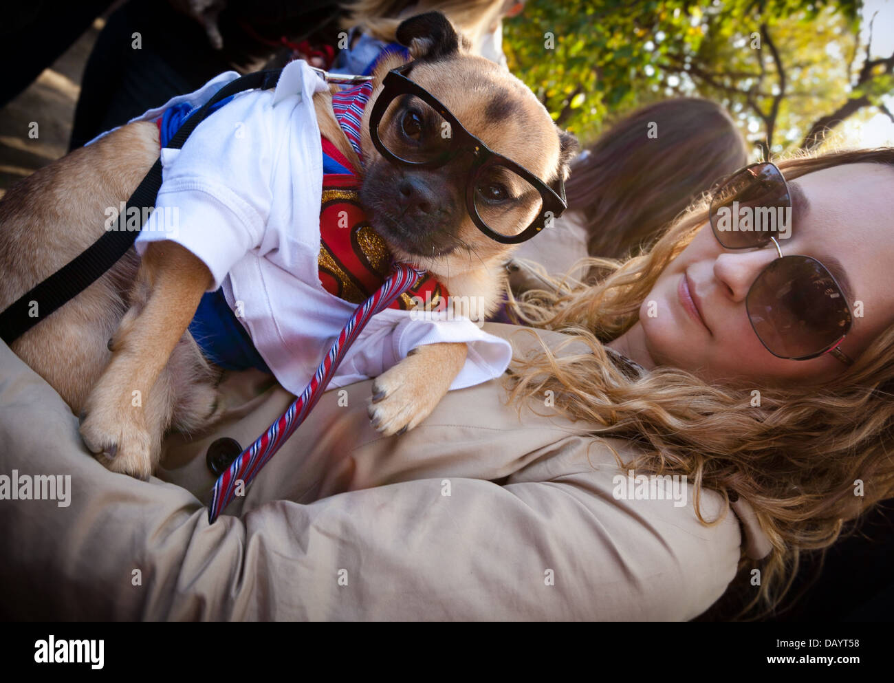 A woman and her dog, who is dressed as Clark Kent from the Superman comics, attend a Halloween costume contest in New York City. Stock Photo