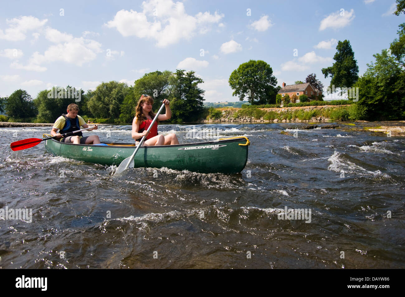 Canoeists in open canoe paddling down the River Wye at The Warren Hay on Wye Powys Wales UK