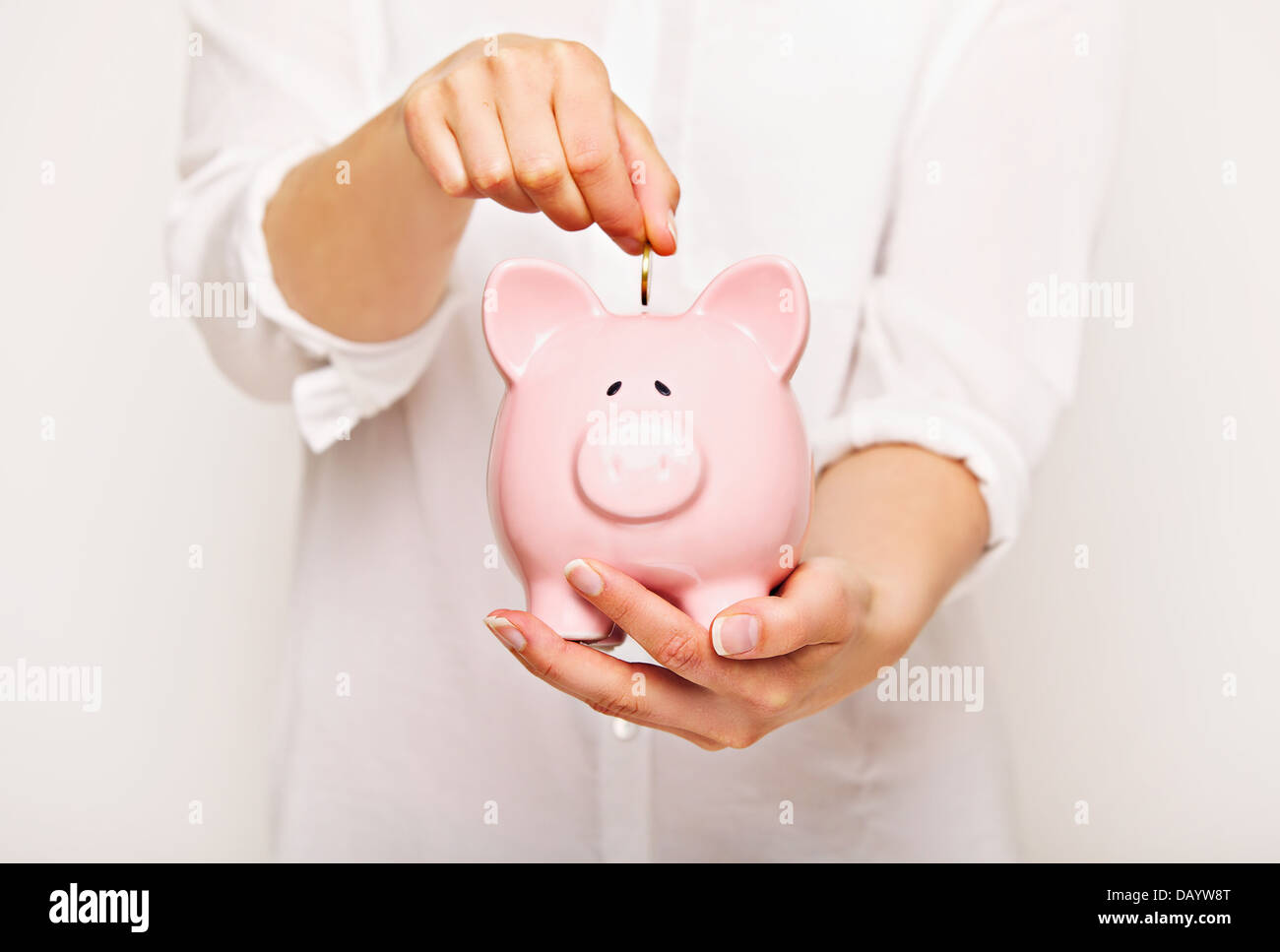 Woman inserting coin in a piggy bank Stock Photo - Alamy