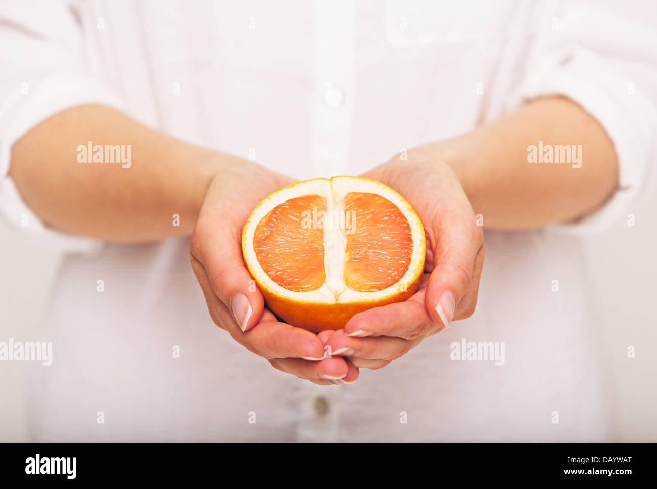 Sliced orange in the hands of a woman Stock Photo