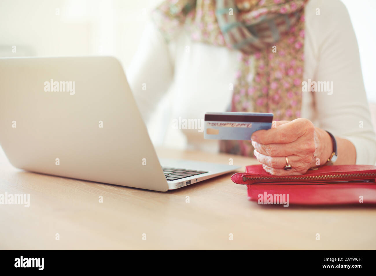 Senior woman's hand holding a credit card while in front of the laptop shopping online Stock Photo
