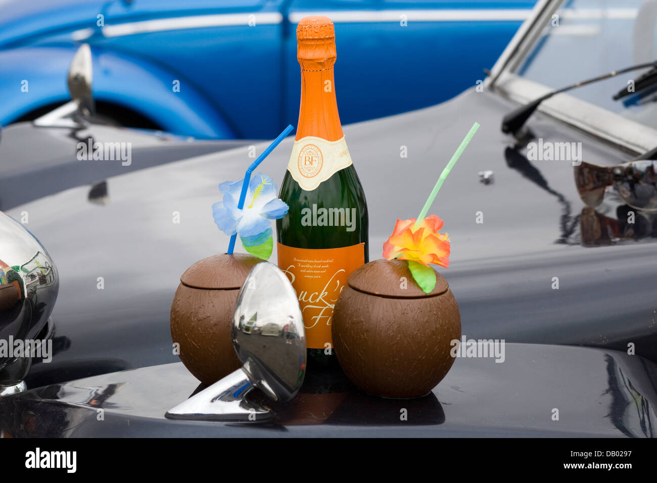 Bottle of Bucks Fizz with plastic Coconut shells and flowers on bonnet of a VW Beetle Stock Photo