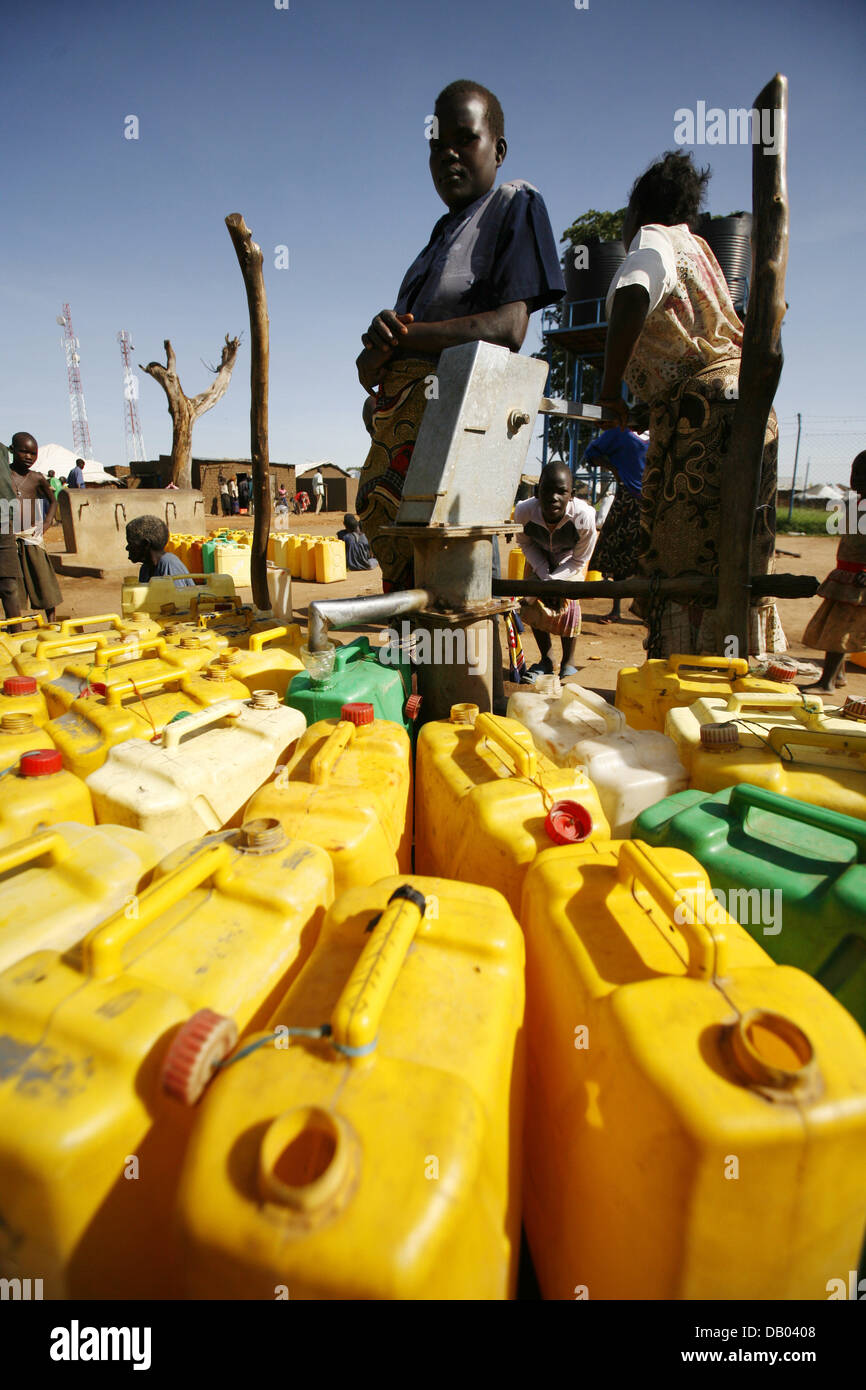Refugees fill plastic containers with water at the well at refugee camp