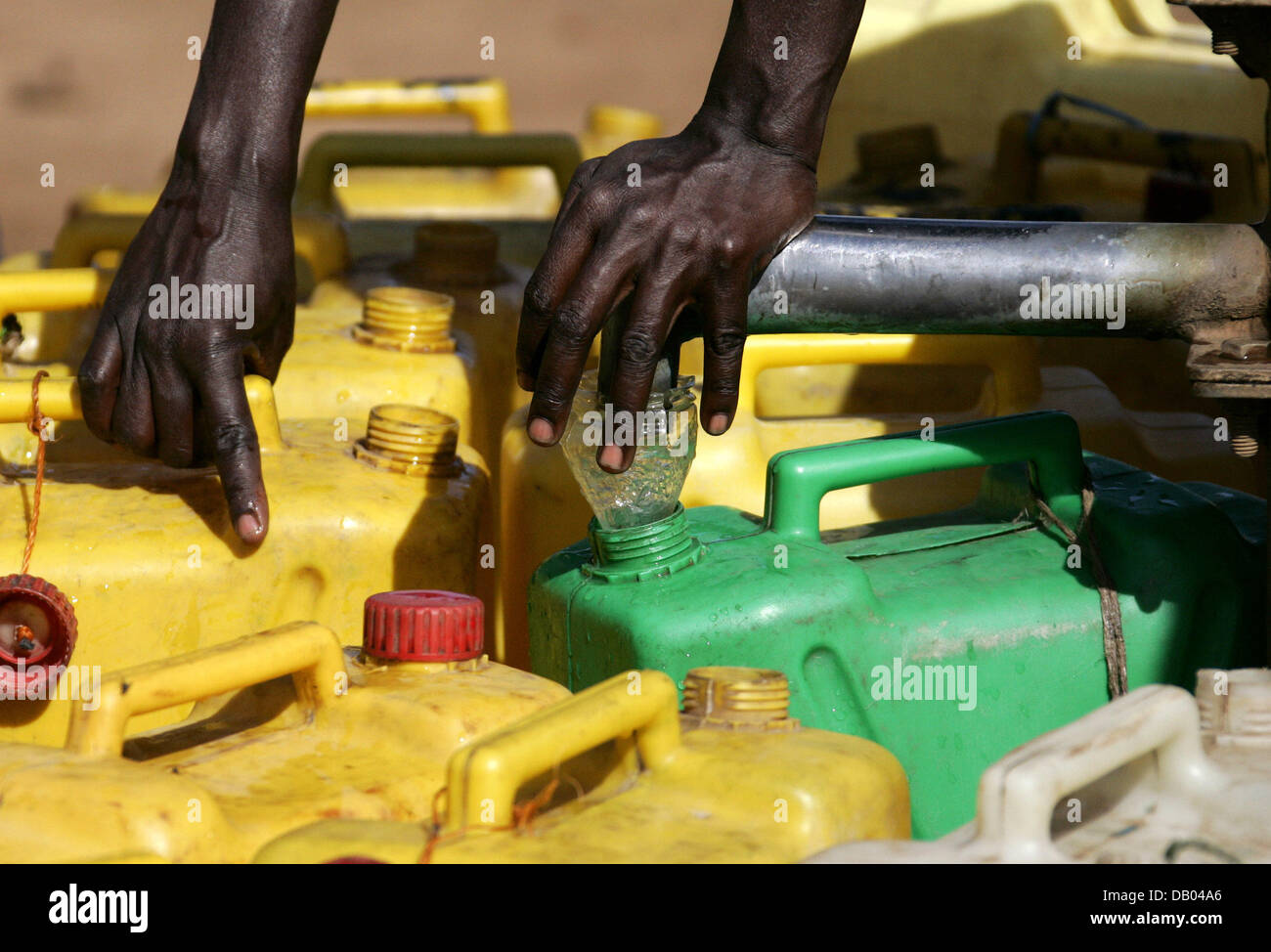 A refugee fills plastic containers with water at the water place at