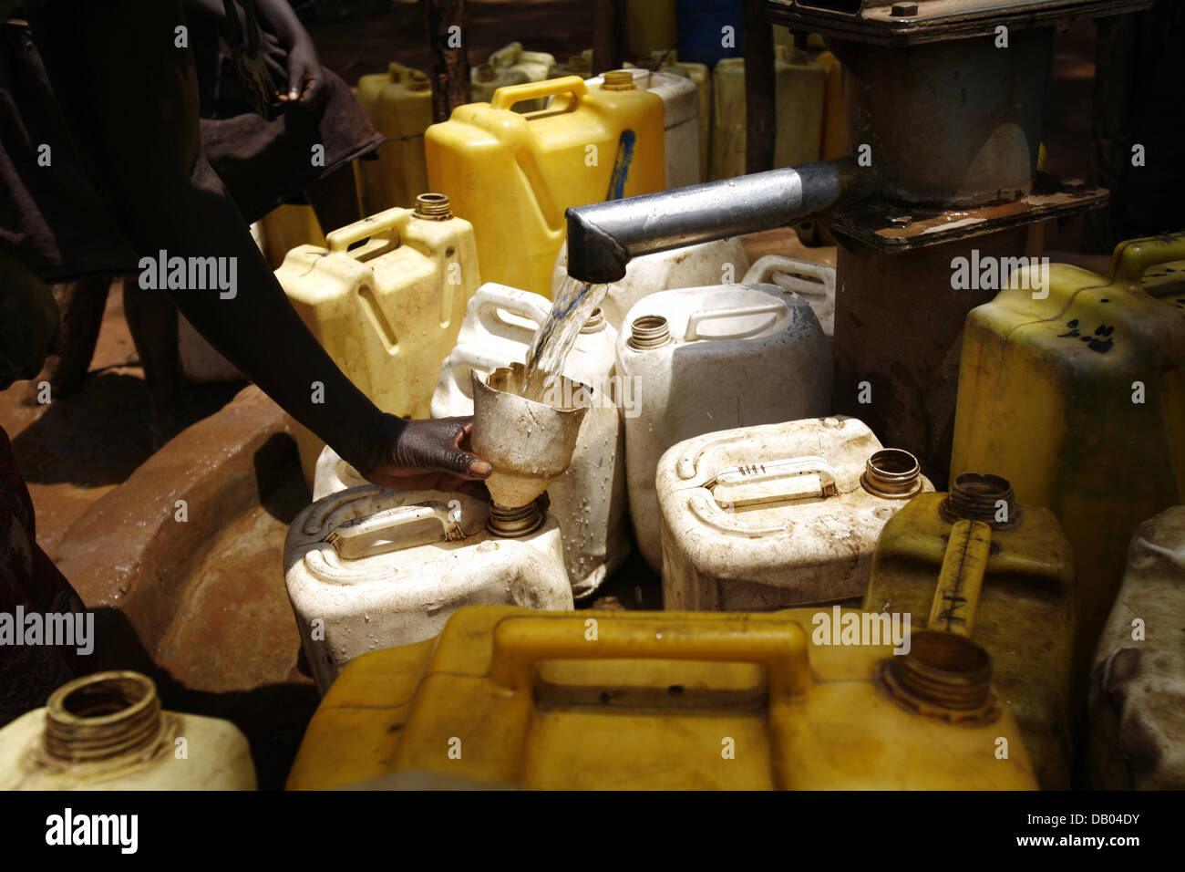 Refugees fill plastic containers with water at the well of a refugee